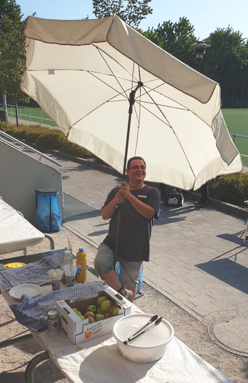Mann draußen unter einem Sonnenschirm am Bufett
