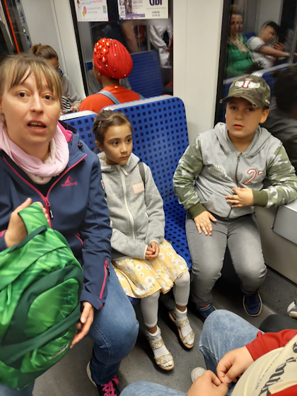 Ein Mädchen, ein Junge und eine Erwachsene sitzen in der S-Bahn