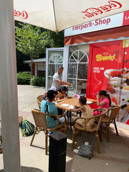 Kinder und der Sensei an einem Tisch vor dem Tierpark-Shop